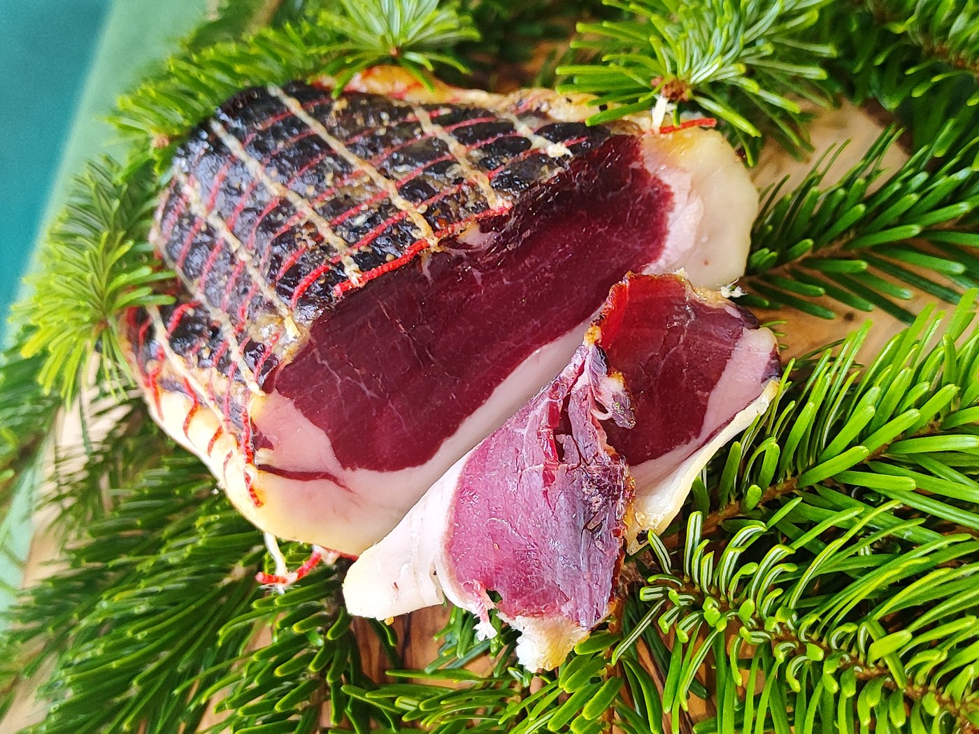 Luftgetrockneter Wildschweinschinken am Stück vor Tannengrün